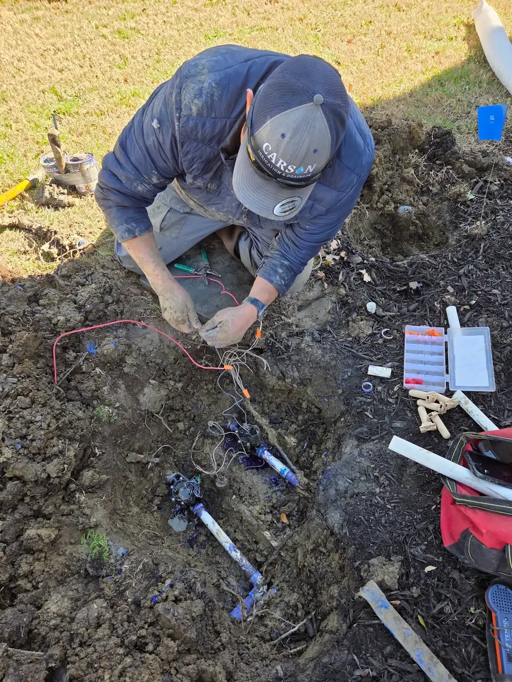 Carson technician wiring irrigation valves in trench