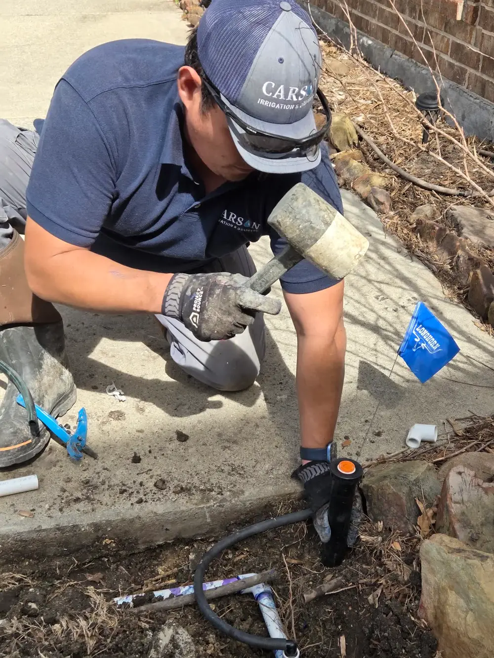 Carson tech working on valve near stone landscape border