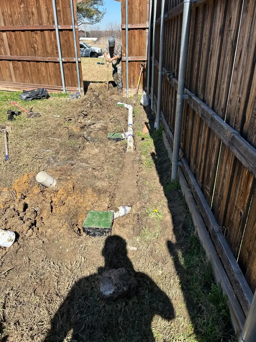 Drainage installation along fence line in backyard